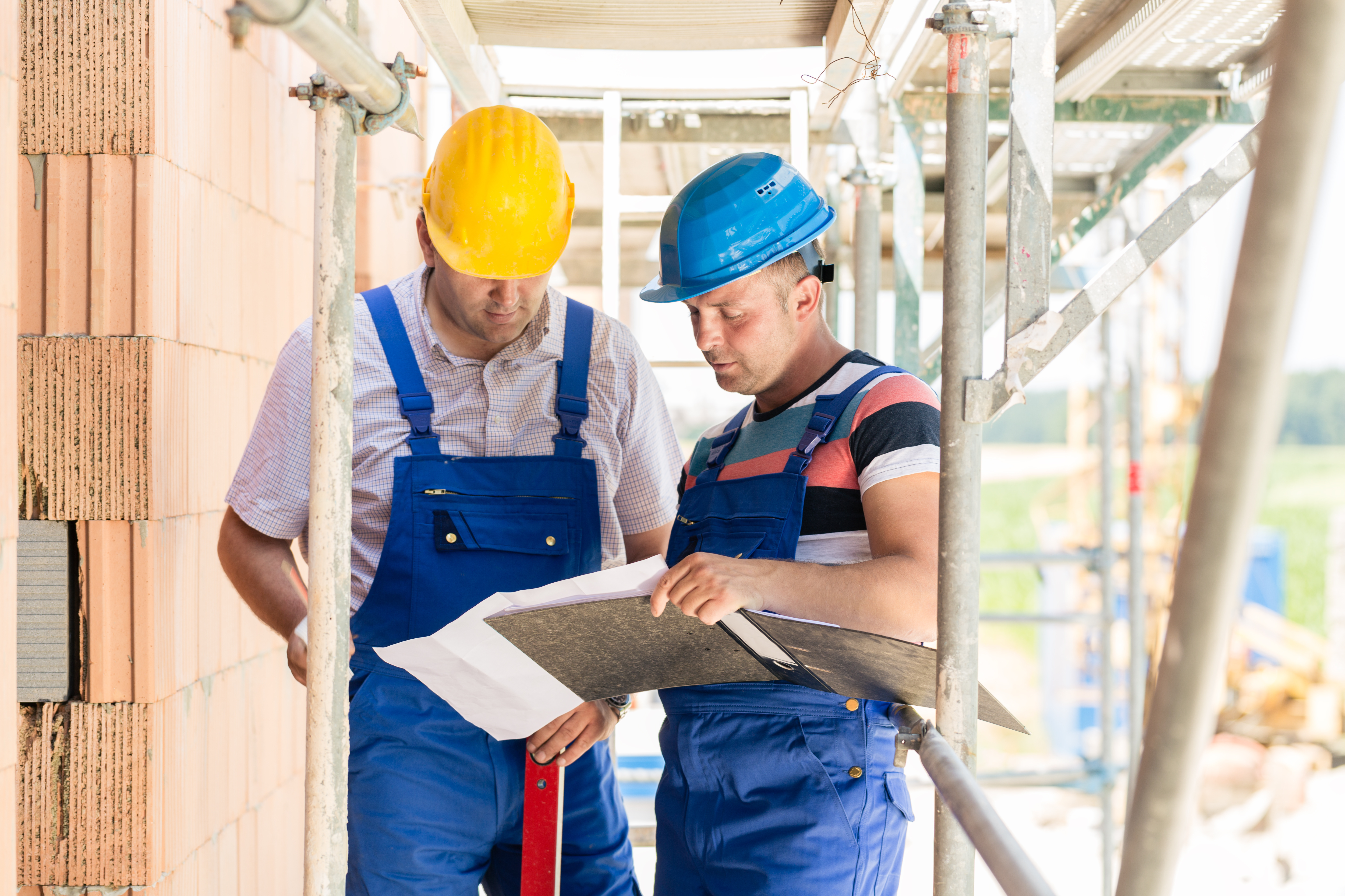 Zwei Handwerker mit einem geöffneten Ordner in der Hand
